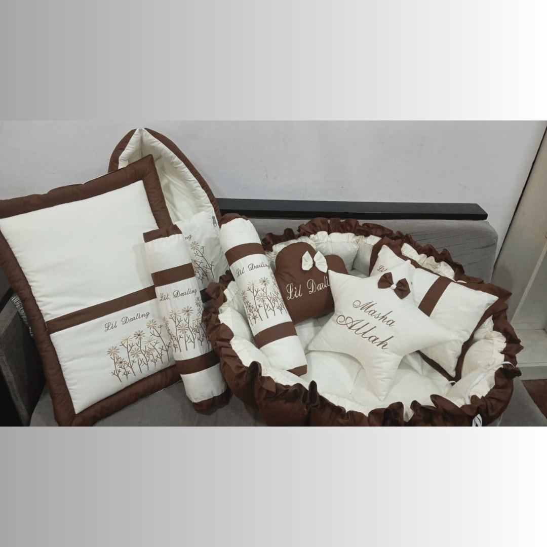 Brown and white baby crib set with decorative elements on a plain background