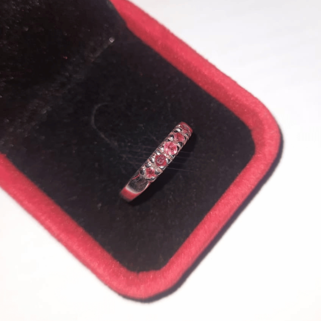 Silver ring with red stones on a black and red jewelry box