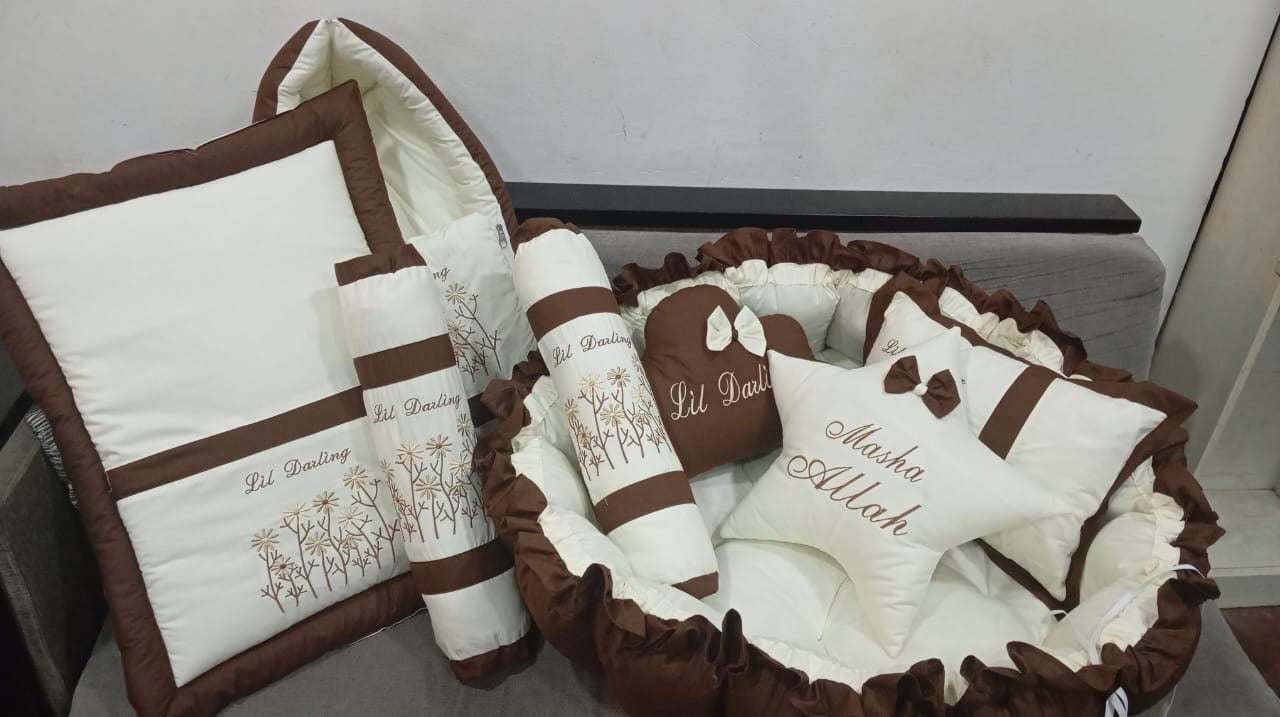 Brown and white baby crib set with embroidered designs on a white background